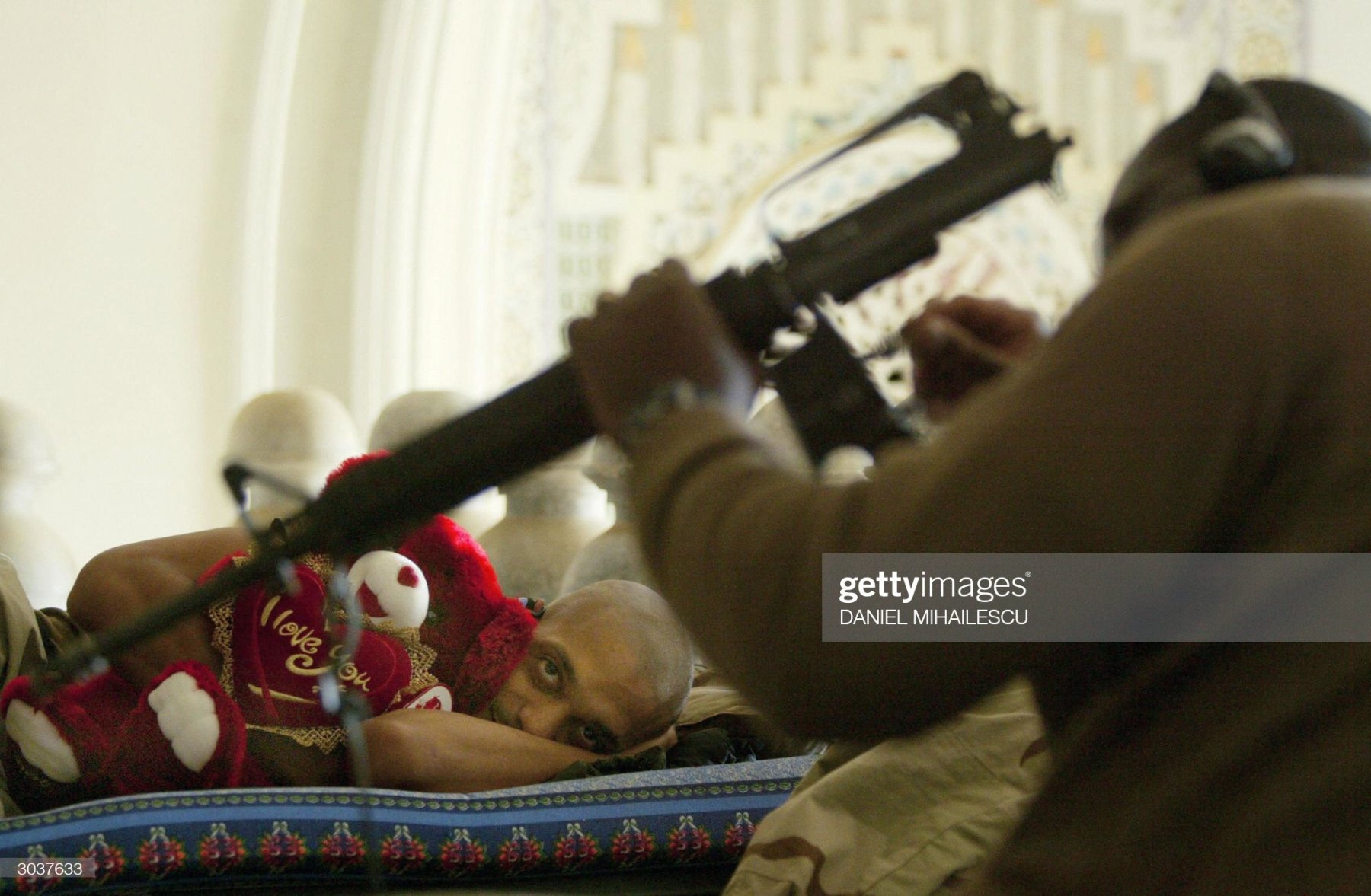 TIKRIT, IRAQ:  US Army Staff Sergeant Temu Gibson (L) from the 4th Infantry Division Ironhorse hugs a teddy bear, a gift from his wife, while he speaks to a comrade cleaning a weapon in Saddam Hussein's hometown Tikrit, north of Baghdad, 03 March 2004. Over 700 military personnel will by leaving until 15 March 2004 back to their homebase in Texas. AFP PHOTO/Daniel MIHAILESCU  (Photo credit should read DANIEL MIHAILESCU/AFP via Getty Images)