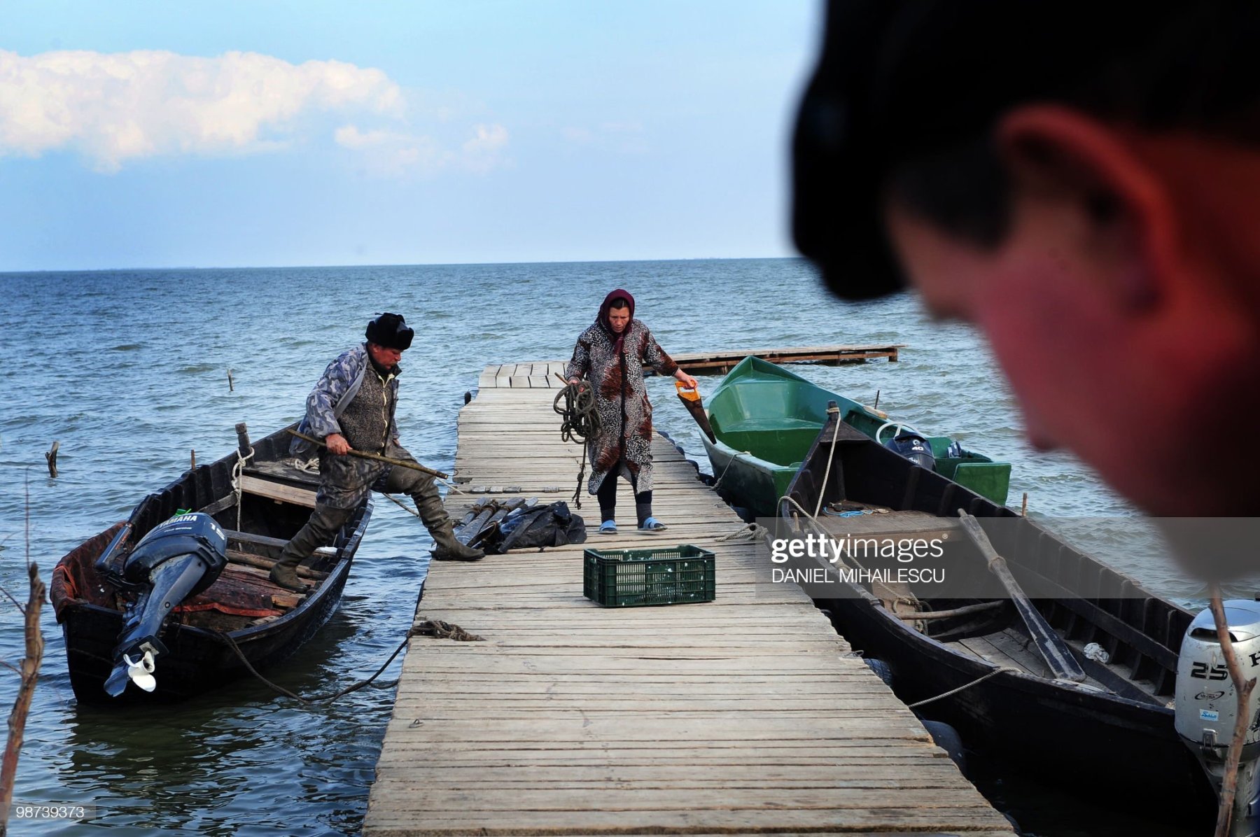 TO GO WITH AFP STORY BY Isabelle WESSELINGH A Lipovan fisherman is helped by his wife as he unloads belongings from his boat on lake Razelm in Sarichioi village, 250kms east of Bucharest, on April 3, 2010. The Lipovans fled religious persecutions in Russia 300 years ago. Exiled to the Danube delta, in a far-flung corner of Romania, they lived through Ottoman domination and a communist dictatorship.Lipovans are officially about 38,000 in Romania, a country of 22 million, but they are most likely around 100,000 according to historians and church registers. AFP PHOTO DANIEL MIHAILESCU (Photo credit should read DANIEL MIHAILESCU/AFP via Getty Images)